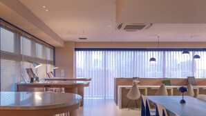 A modern conference room with round tables, blue chairs, and pendant lighting. - THE BASEMENT HOTEL Osaka Honmachi  (Osaka)