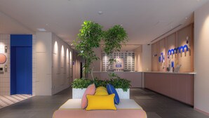 A modern hotel lobby with a reception desk, a seating area with cushions, and a large plant. - THE BASEMENT HOTEL Osaka Honmachi  (Osaka)