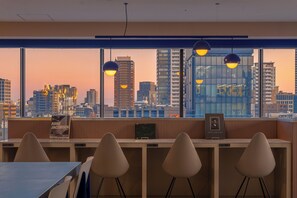 Et moderne kontor med udsigt over byens skyline, et træbord og tre hvide stole.