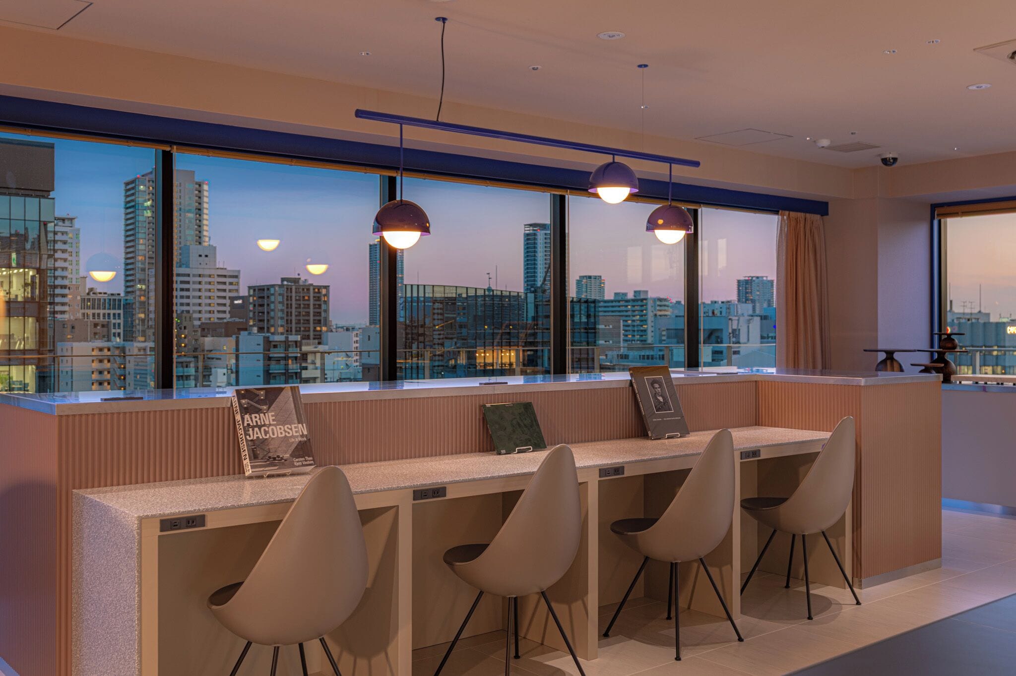 A modern hotel lobby with a city view, a reception desk, and seating area.