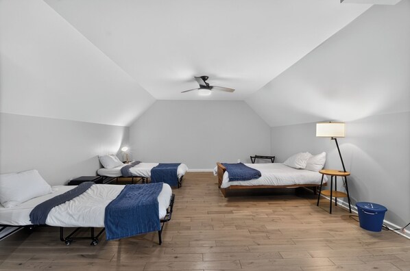 A room with three beds, a ceiling fan, a floor lamp, and a trash bin. - Entire Home in Fountain Square (Indianapolis)