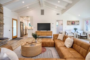 A modern living room with a large sofa, a coffee table, and a TV in the background. - Sunridge Lookout by Avantstay Big Backyard Oasis + Patio, Central Location (Pebble Beach)