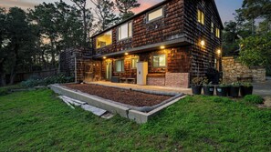 A modern two-story house with a wooden exterior, a stone wall, and a well-maintained garden with potted plants. - Sunridge Lookout by Avantstay Big Backyard Oasis + Patio, Central Location (Pebble Beach)