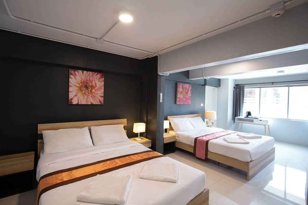 Une chambre d’hôtel avec deux lits, un bureau et une fenêtre.