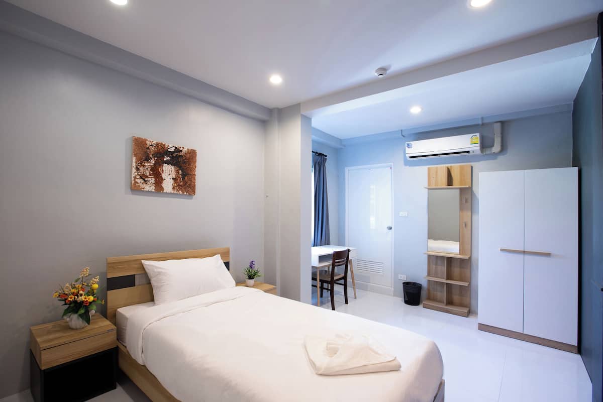 Une chambre d’hôtel moderne avec un lit bien fait, un bureau et une armoire.