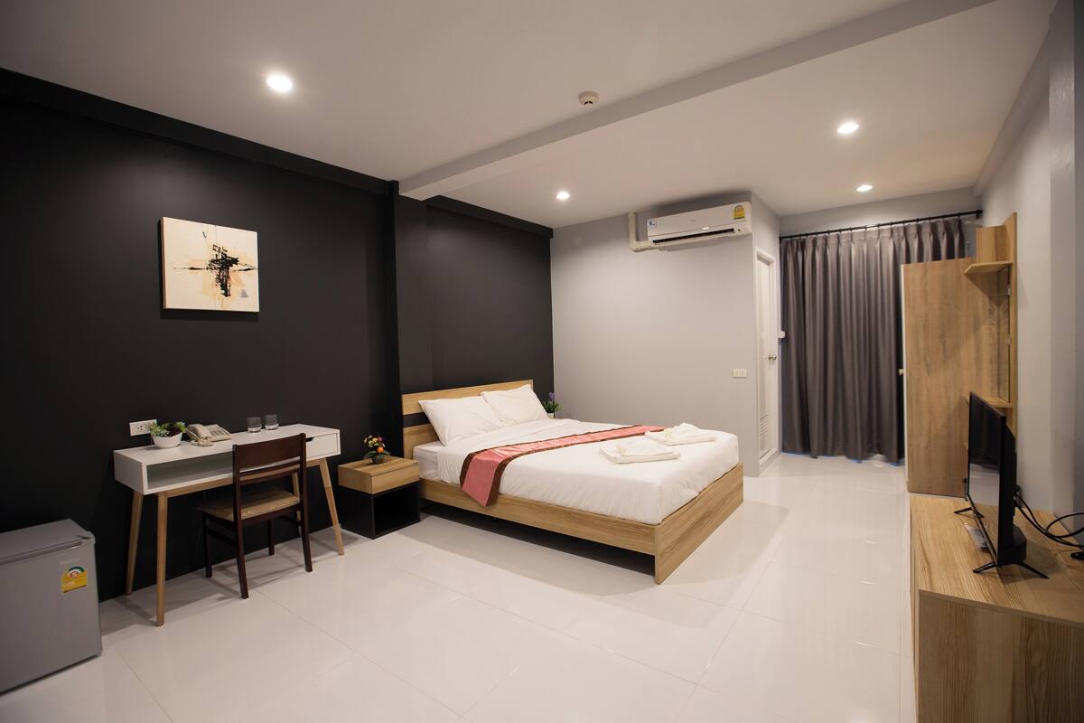 Une chambre à coucher moderne, équipée d’un lit, d’un bureau, d’une chaise et d’un téléviseur.