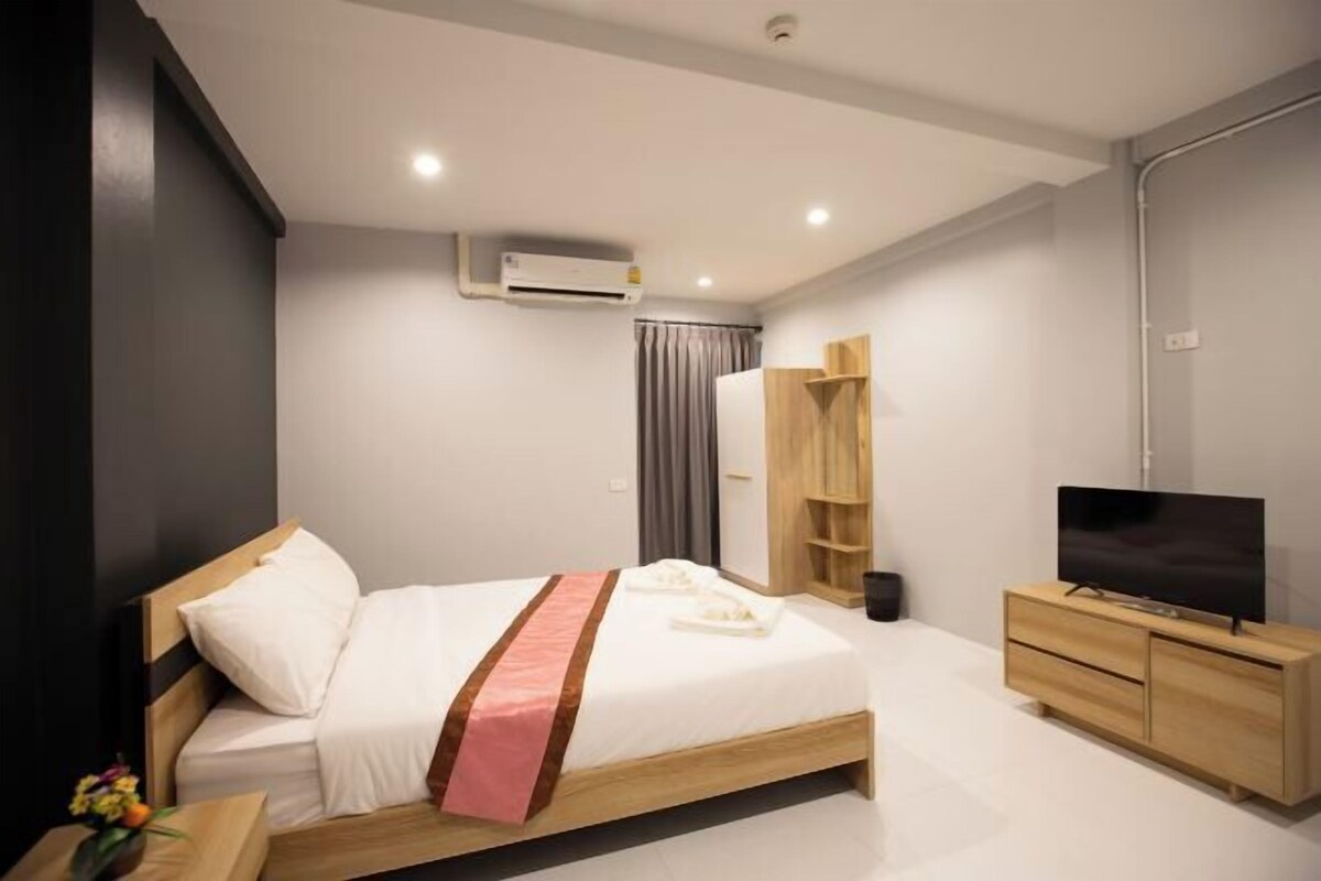 Une chambre d’hôtel moderne équipée d’un lit, d’une télévision, d’une armoire et d’un appareil de climatisation.