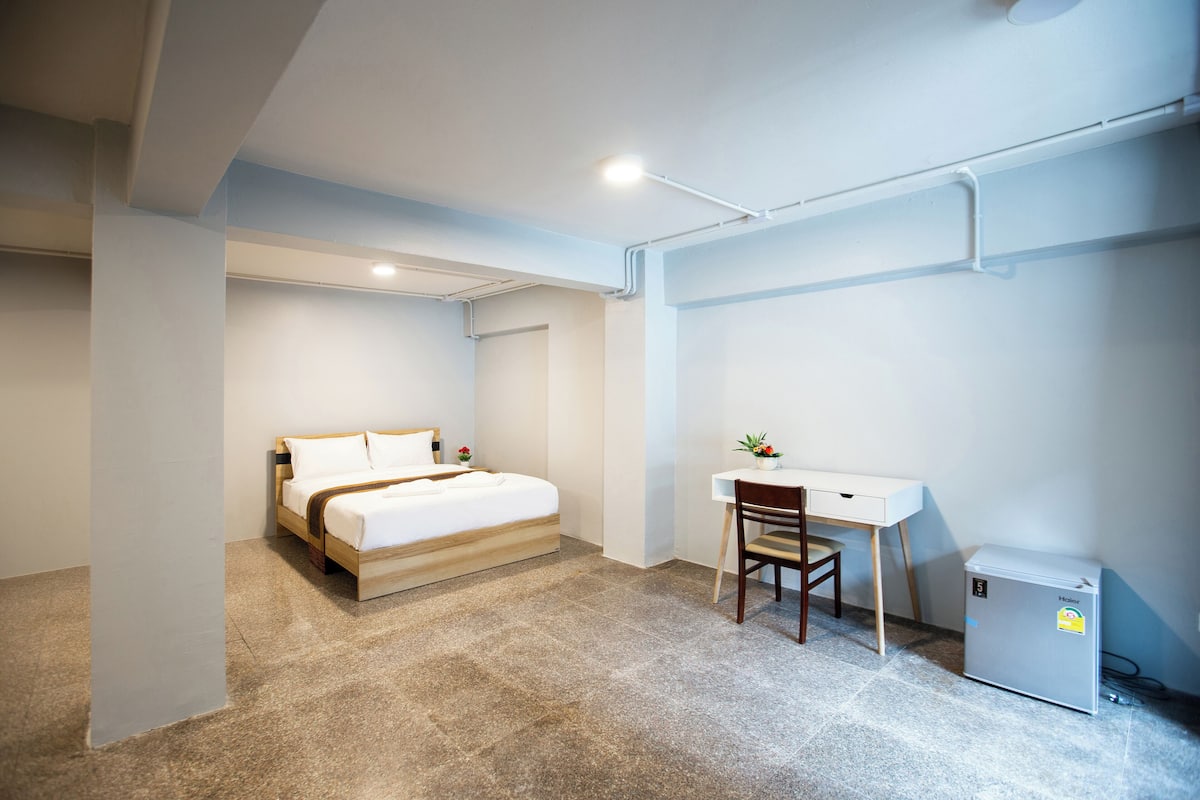 Une chambre à coucher avec un lit, un bureau et un petit réfrigérateur.