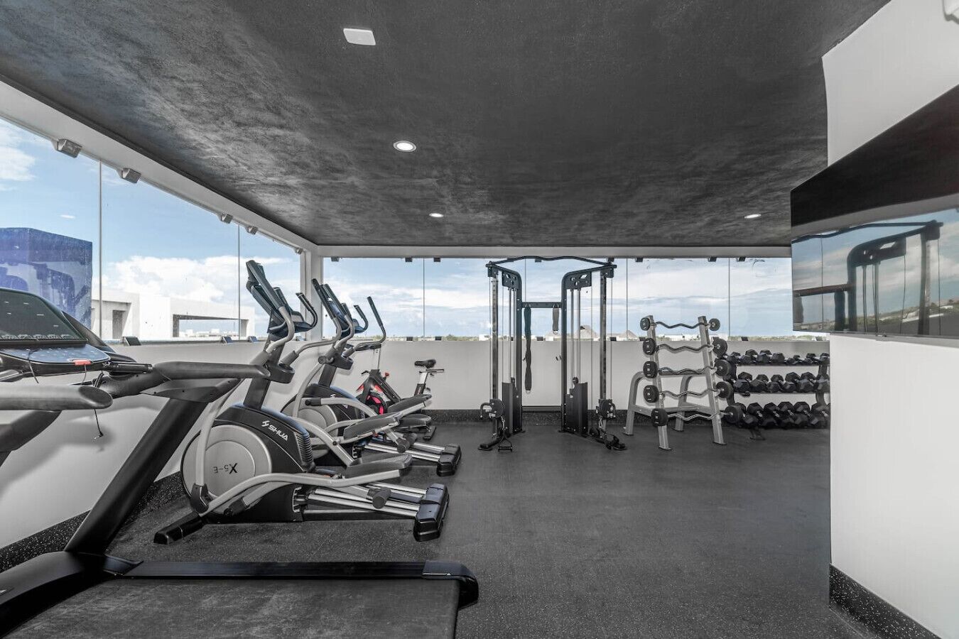 Ein Fitnessstudio mit Cardiogeräten, Krafttrainingsgeräten und Kurzhanteln.