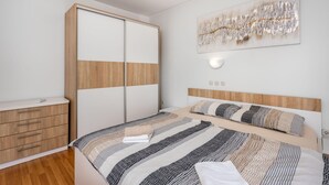 Een slaapkamer met een bed, een kledingkast, een nachtkastje en een wandlamp.