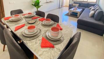 Un coin repas avec une table en marbre dressée pour six personnes, entourée de chaises.