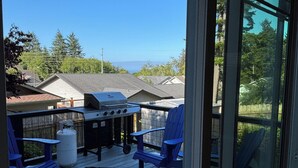 A deck with blue chairs, a grill, and a propane tank.