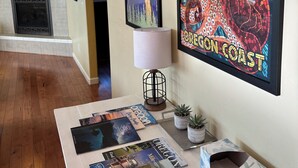 A room with a fireplace, a table with travel magazines, and two framed posters on the wall.