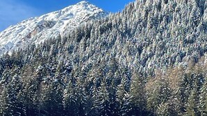 Une montagne enneigée, avec une maison en bois au premier plan.