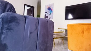 A modern living room with a sofa, a coffee table, and a television. - Luxury studio with Jacuzzi in a serene REstate (Lekki)