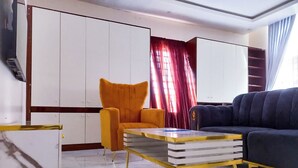 A modern living room with a sofa, a yellow armchair, a coffee table, and a wardrobe. - Luxury studio with Jacuzzi in a serene REstate (Lekki)