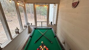 A pool table in a room with large windows, wooden walls, and a sign reading "Ice Cold Watermelon". - Our Happy Place is located in the gated community of Holly Lake Ranch. (Hawkins)