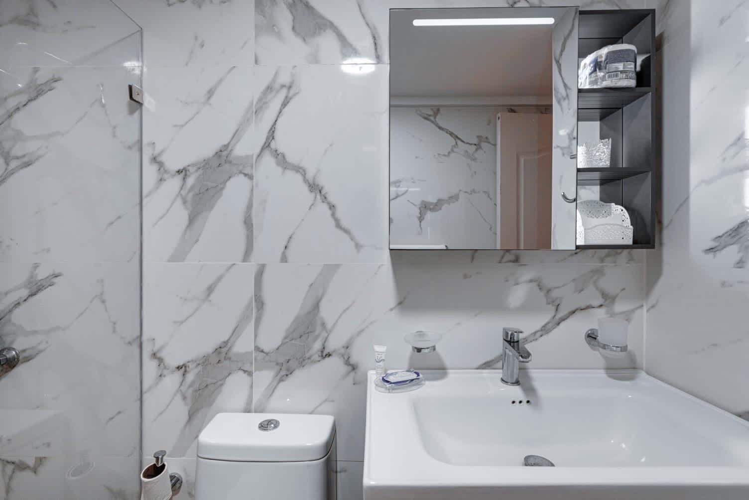 A bathroom with a white sink, a toilet, and a mirror above the sink.