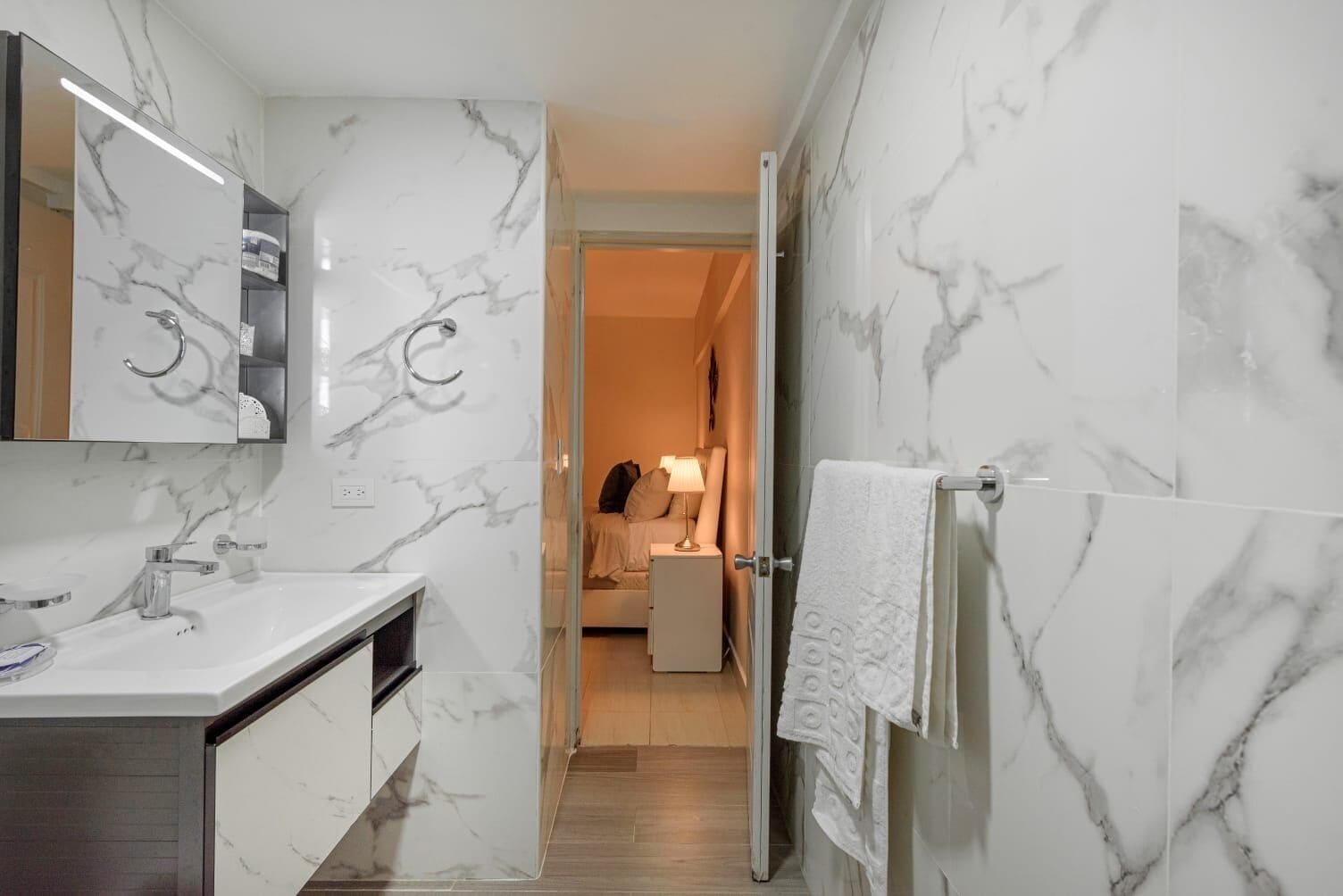 A modern bathroom with a marble backsplash, a sink, and a mirror.