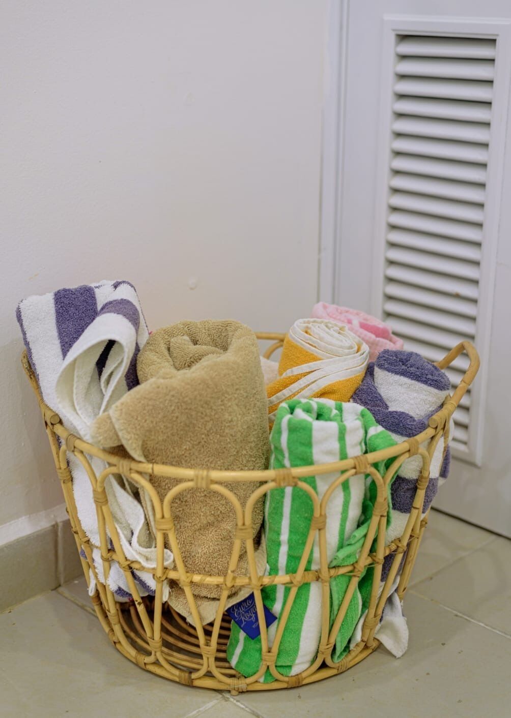 A wicker basket filled with various towels and a plush toy.