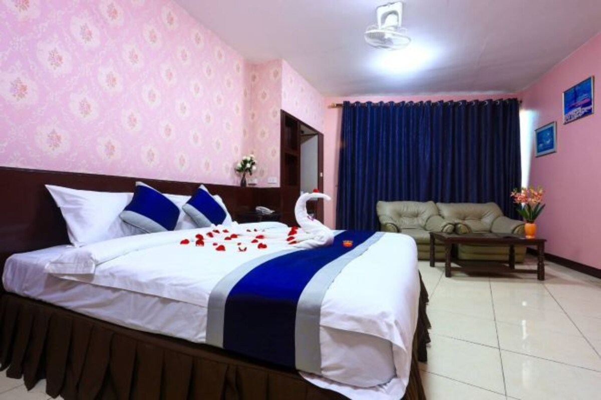 A hotel room with a bed, a sofa, a coffee table, and a wall with a floral pattern.