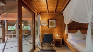 A wooden room with a bed, a chair, a lamp, and a picture on the wall. - Sungai Villa by Betterplace (Canggu)
