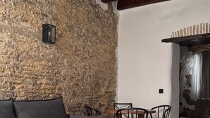 A room with a stone wall, a wooden ceiling, a sofa, a small round table, and a tiled floor with star patterns.