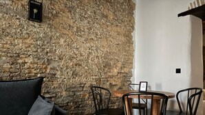 A room with a stone wall, a black sofa, and a wooden table with chairs.