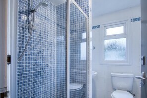 Une salle de bain avec une douche à parois de verre, des toilettes et une fenêtre.