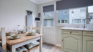 A compact kitchen with a wooden table set for dining, a built-in sink, and a view of neighboring houses.