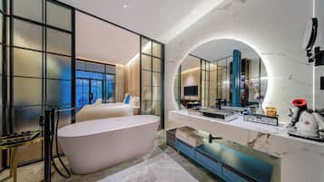 A modern bathroom with a freestanding bathtub, a large mirror, and a vanity with a marble countertop.