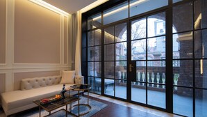 A modern living room with a sofa, a coffee table, and a large window with a view of a brick building. - SECLUSION TANG (Luoyang)