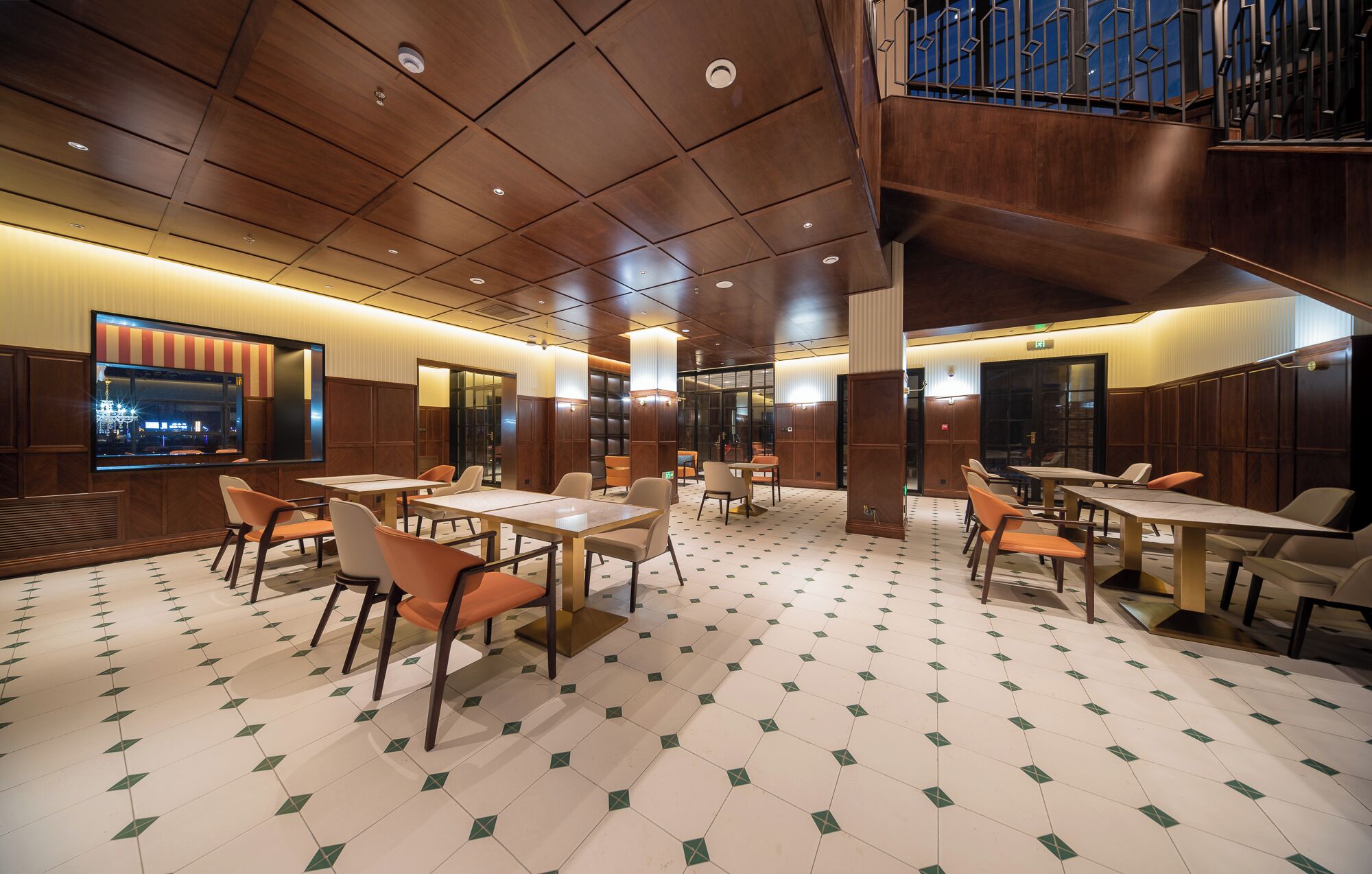 A spacious dining area with multiple tables and chairs, a large window with a view, and a wooden ceiling.