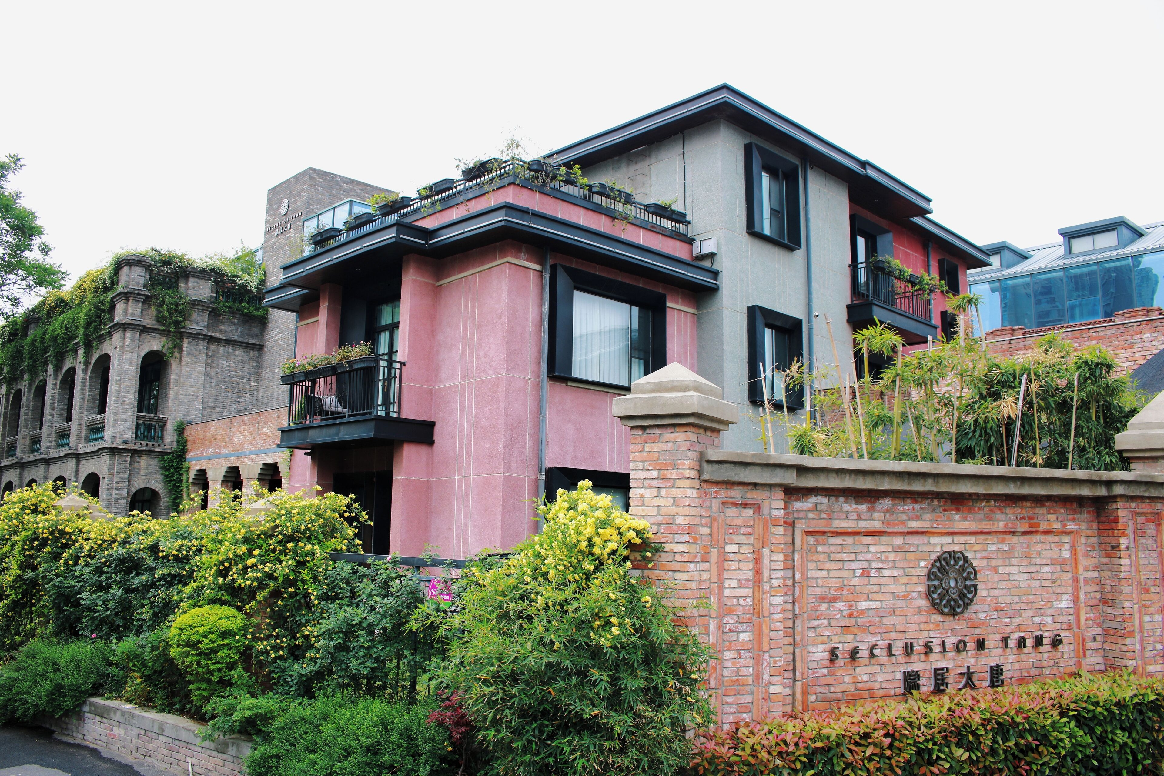 Un edificio de varios pisos con fachada de ladrillo, balcones y abundante vegetación.