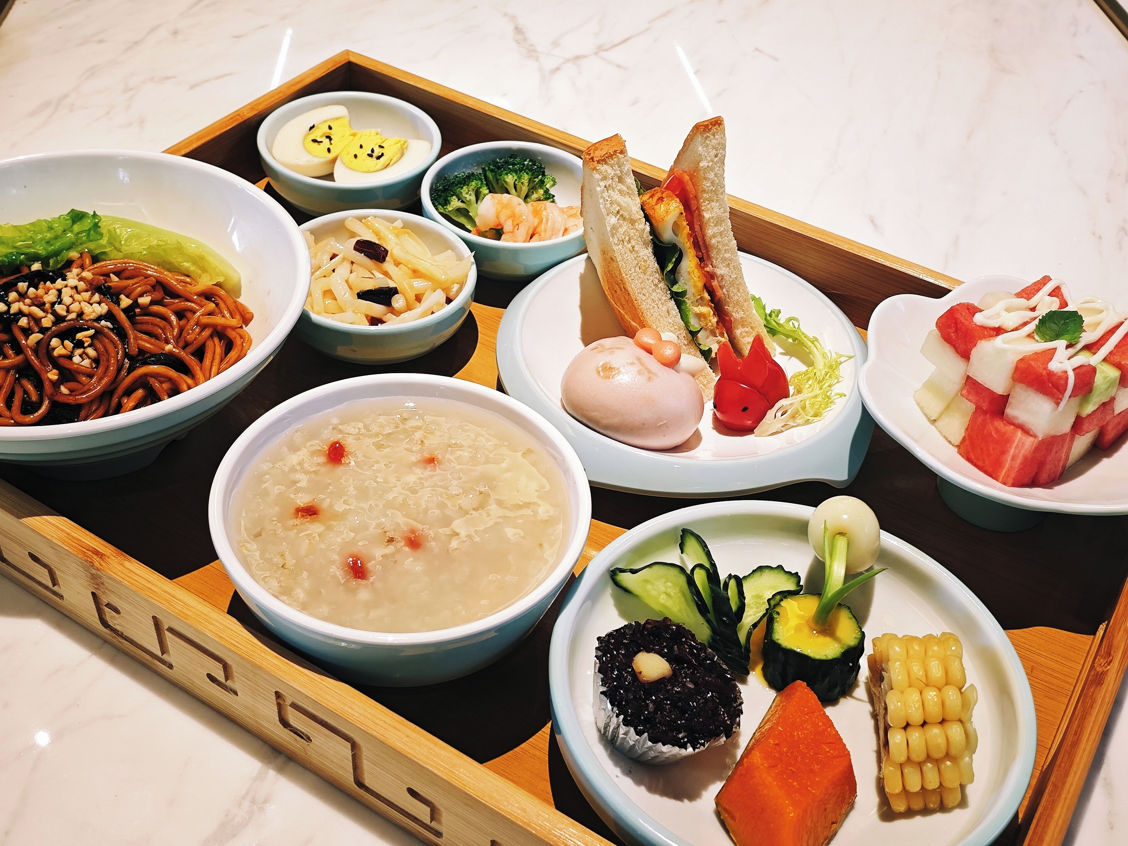 A variety of dishes including noodles, soup, and vegetables on a tray.