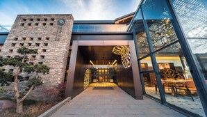 A modern building with a brick facade, large glass entrance, and decorative golden elements. - SECLUSION TANG (Luoyang)