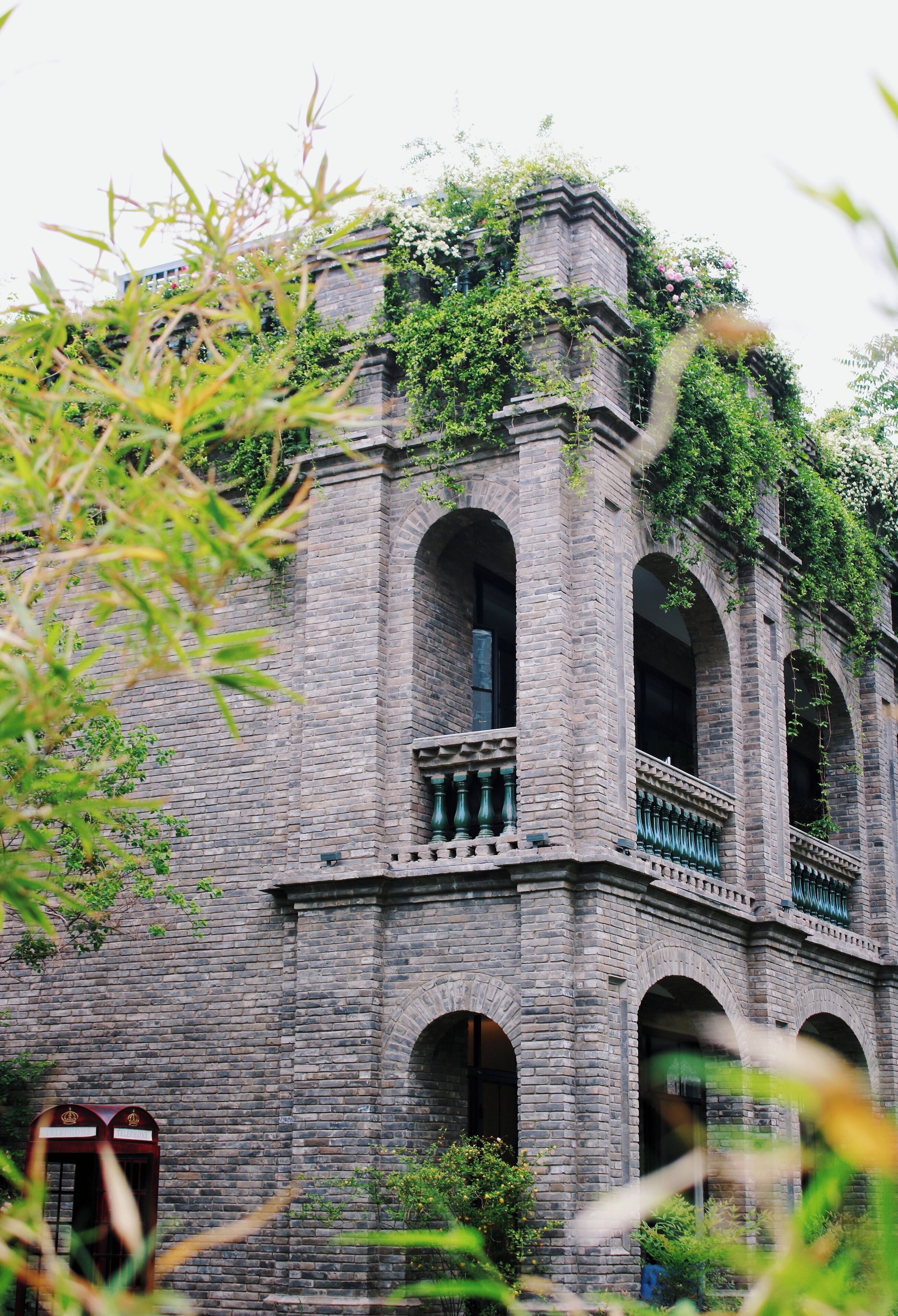 A historic building with arched windows and balconies, surrounded by greenery.