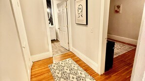 A hallway with wooden flooring, a patterned rug, and a framed artwork on the wall. - Luxe 2-bedroom apartment near university of Rochester and hospitals.pets allowed (Rochester)