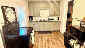 A compact kitchen with a black stove, a microwave, and a sink. There is a clock on the wall and cabinets above the counter. - Luxe 2-bedroom apartment near university of Rochester and hospitals.pets allowed (Rochester)