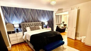 A modern bedroom with a large bed, a nightstand, a dresser, and a vanity with a mirror. - Luxe 2-bedroom apartment near university of Rochester and hospitals.pets allowed (Rochester)