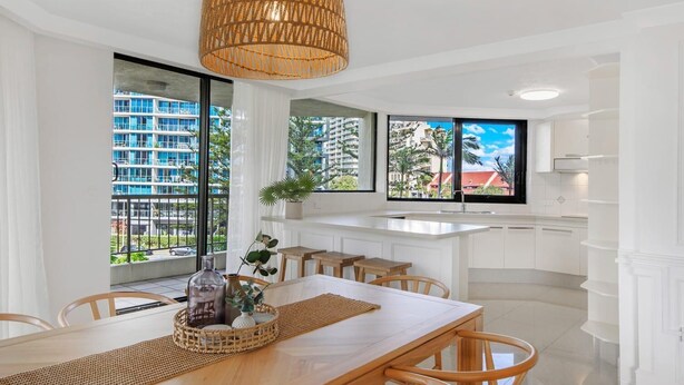 Una cocina moderna con armarios blancos, una isla grande y vistas a una zona residencial.
