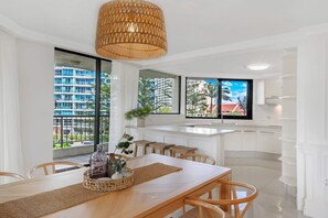 Uma cozinha moderna com armários brancos, uma ilha grande e vista para uma área residencial.