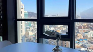 Ein Konferenztisch mit einer Lampe in einem Raum mit großen Fenstern und Blick auf eine Stadtlandschaft.
