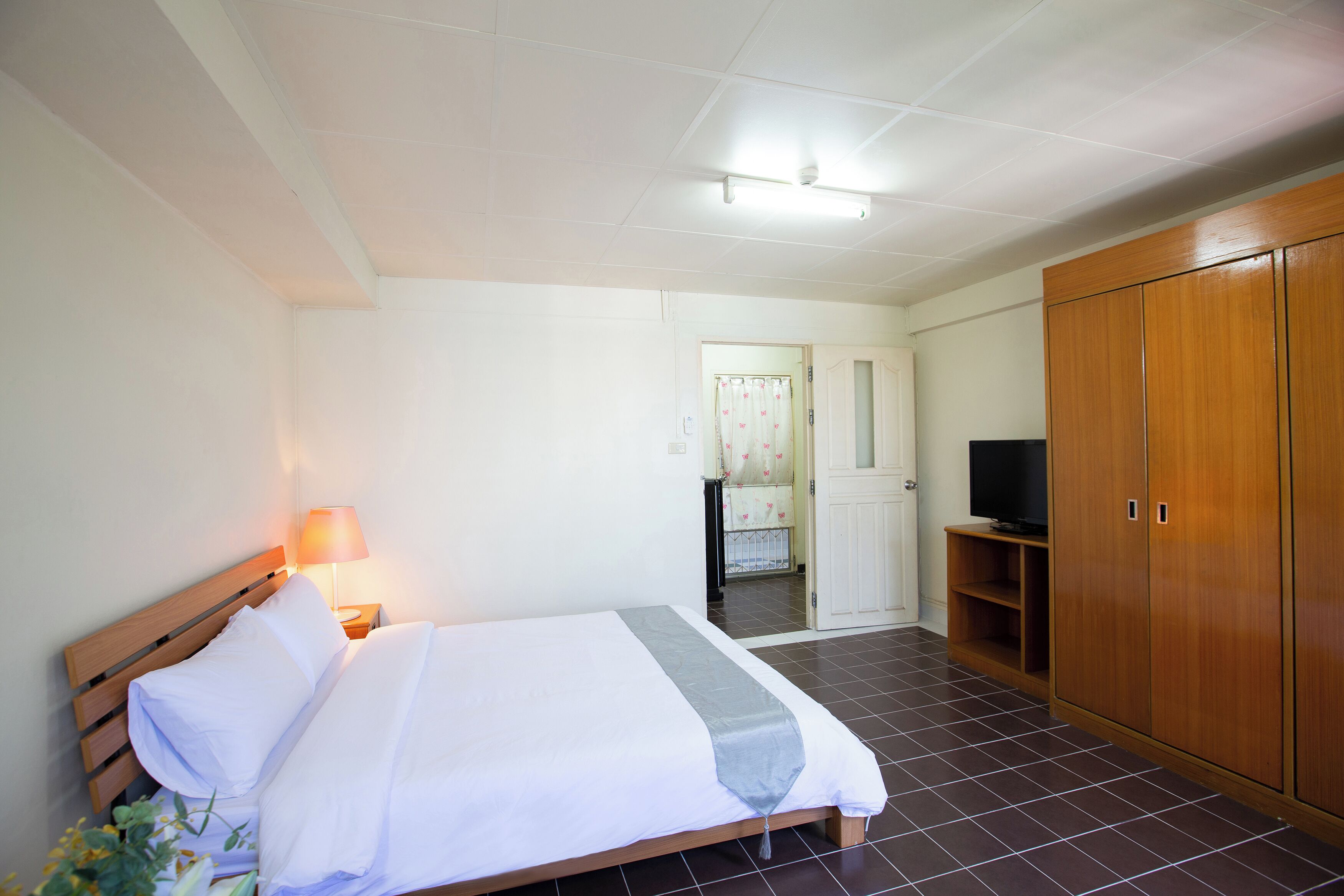 A hotel room with a bed, a TV, a wardrobe, and a bathroom visible in the background.