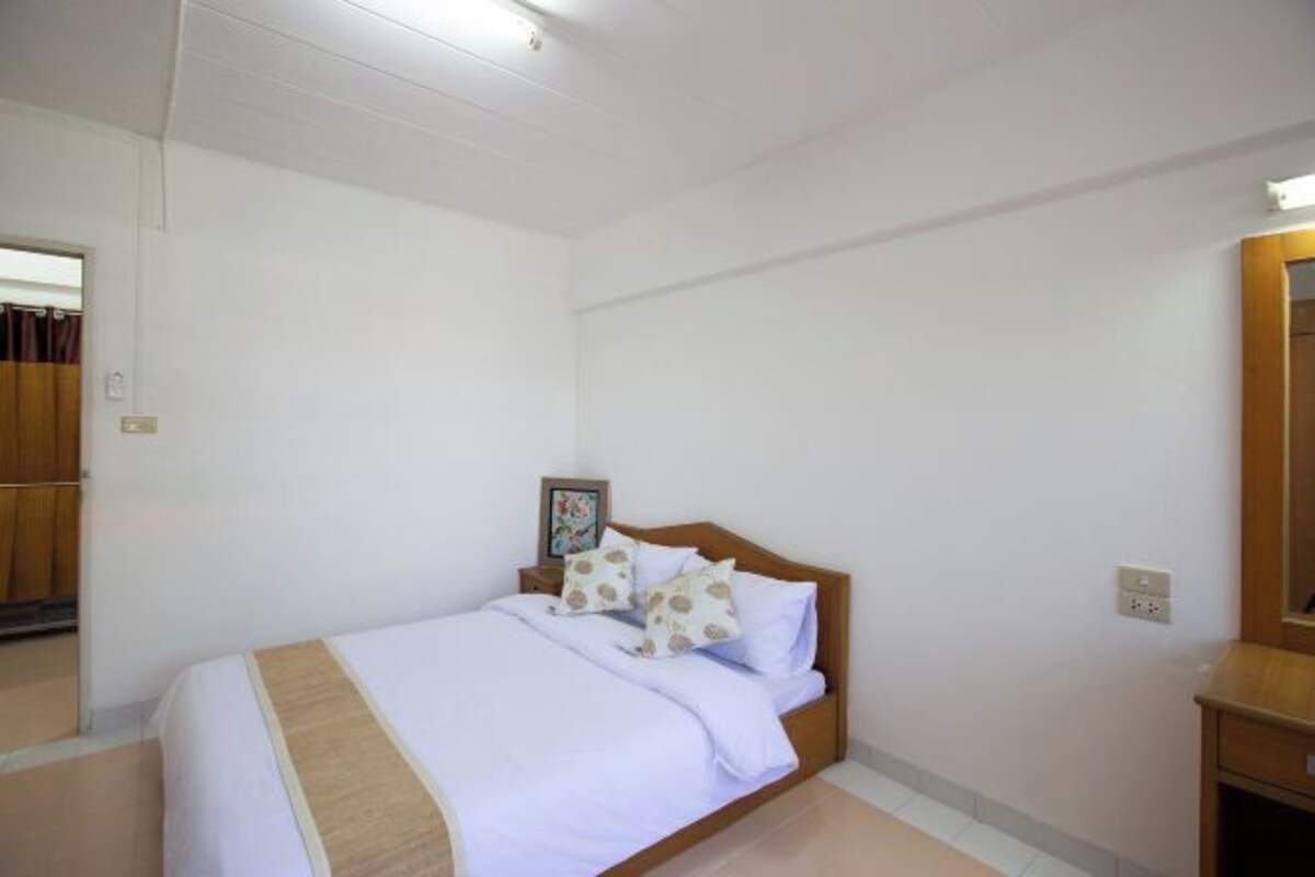 Una camera da letto ordinata con un letto singolo, un comodino e uno specchio.