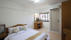 Ein Hotelzimmer mit einem Bett, einem Nachttisch aus Holz, einem Schreibtisch und einem Kleiderschrank.