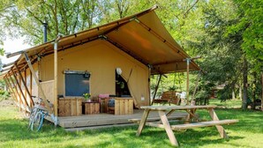 A wooden cabin with a covered porch, a bicycle, and a picnic table. - Luxury Sunshine Tent in Dochamps (Manhay)