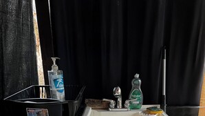 A white portable sink with a soap dispenser and a sponge on a black surface.