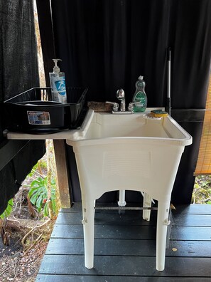 A white portable sink with a soap dispenser and a sponge on a black surface.