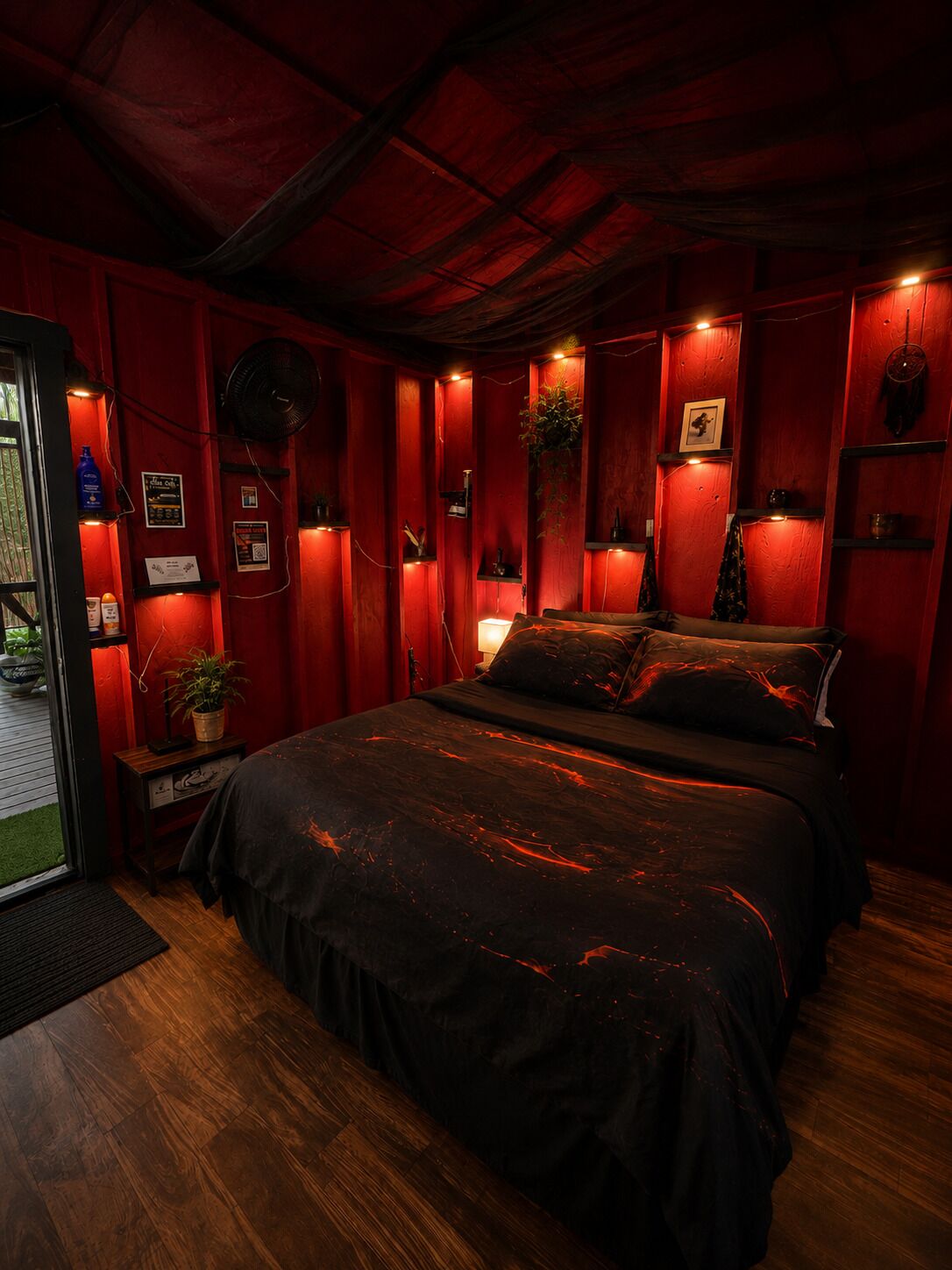 A room with a bed, a small table, a potted plant, and a wall-mounted shelf.